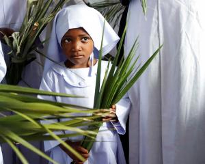 A child holds palm leaves as she attends a Palm Sunday mass at the St Mary’s Legio Maria of...