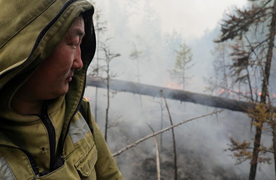 A specialist of Russia's Aerial Forest Protection Service stands near a wildfire in the Sakha...