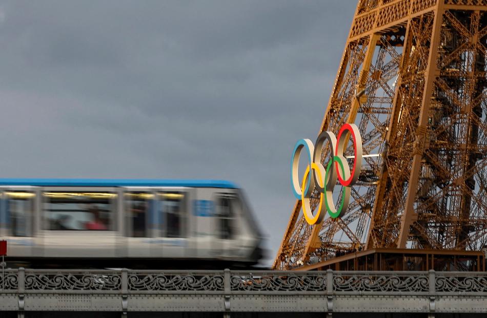 An elevated metro train passes over the Pont de Bir-Hakeim bridge, as the Eiffel Tower displays...