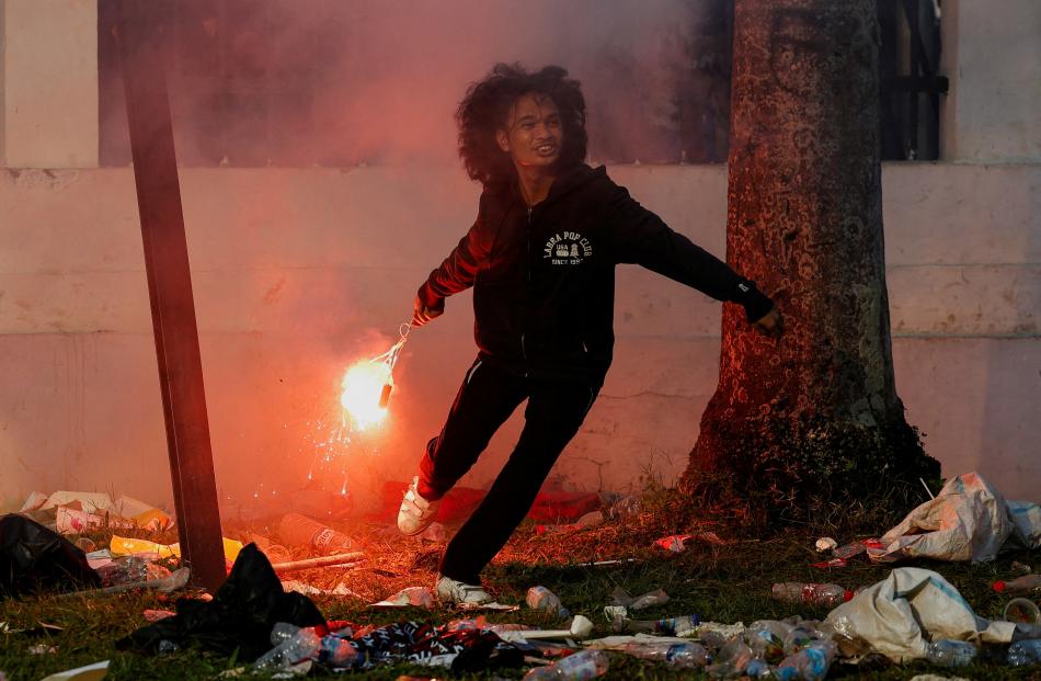 A demonstrator throws a flare during a protest against election law reforms, in Jakarta,...