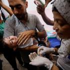 A Palestinian man holds a child being vaccinated against polio at Nasser hospital in Khan Younis...