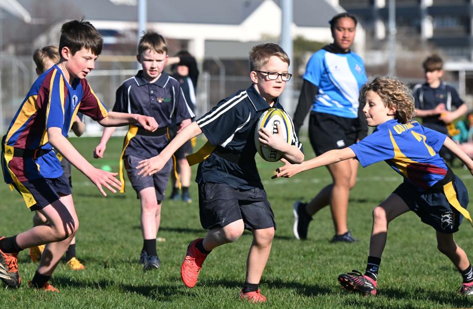 Mason Holden (10, Elmgrove School) tries to zip past Outram School defenders Evan Woodhouse (left...