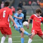 Dunedin City Royals player Raven August boots the ball under the pressure of Nomads players...