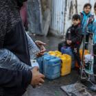 Palestinians carry containers of drinkable water collected from mobile barrels. UNRWA has been...