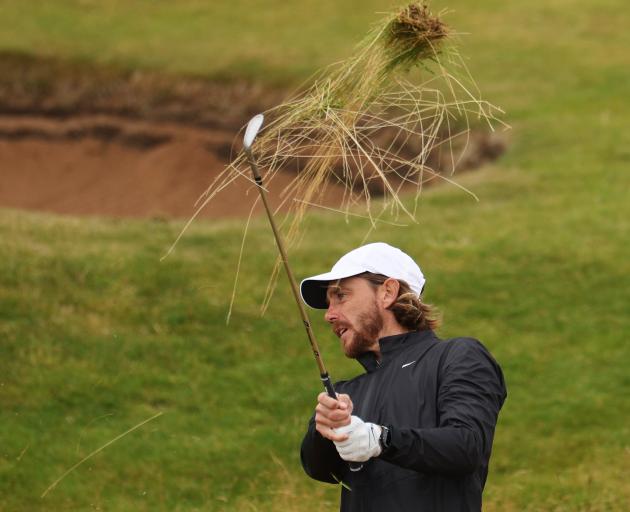 Tommy Fleetwood hacks out a clump of fescue at Royal Troon. Photo: Getty Images