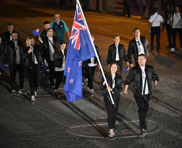 Anna Grimaldi and Cameron Leslie, flag bearers of Team New Zealand, hold their national flag as...