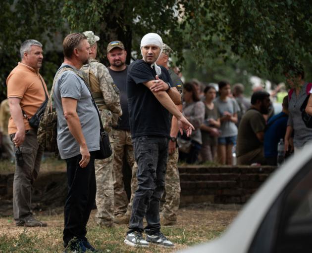 People stand near the Poltava Military Institute of Communications, the site of a Russian missile...