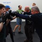 NRG personal trainer Jake Kelly (left) holds punching mitts while Prost-Fit member Andrew Brown...